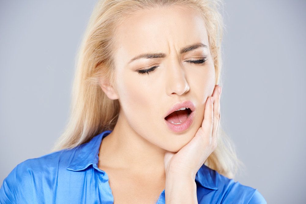 young blond woman with bad tooth ache